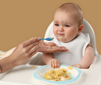 Baby beim entspannten Beikoststart mit Löffel im Hochstuhl